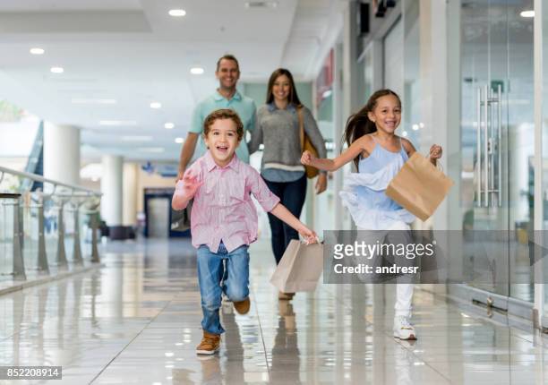 familie einkaufen und läuft auf die kamera in der mall - shoppingcenter stock-fotos und bilder