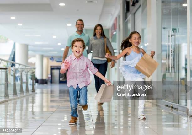 family shopping and running towards the camera at the mall - shopping mall imagens e fotografias de stock