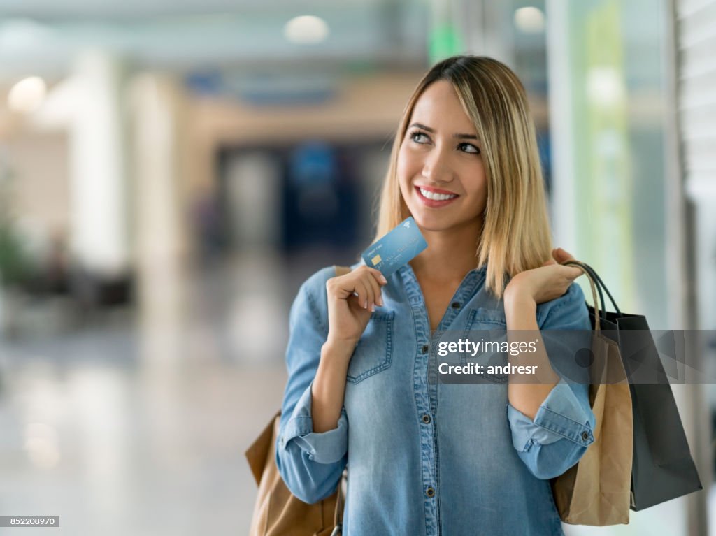 Thoughtful woman shopping with a credit card at the mall