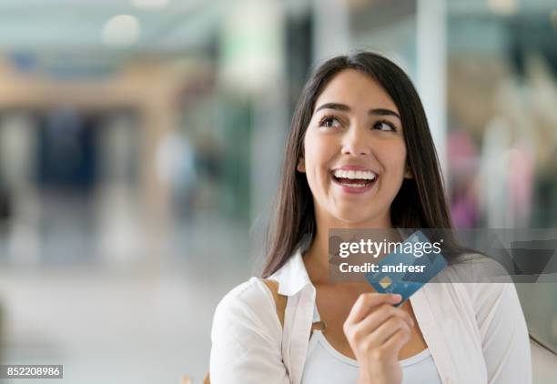 thoughtful woman shopping with a credit card at the mall - loyalty card stock pictures, royalty-free photos & images
