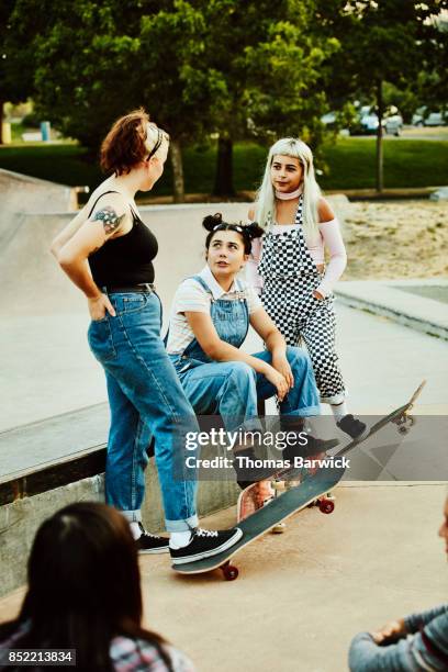 female friends in discussion while skating at skate park - jeans latzhose frau stock-fotos und bilder