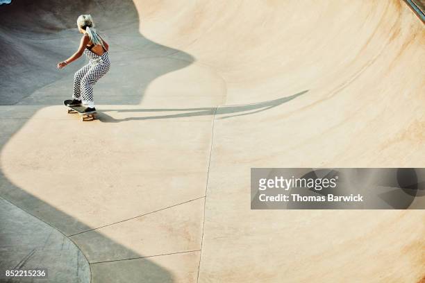 Female skater in bowl in skate park on summer morning