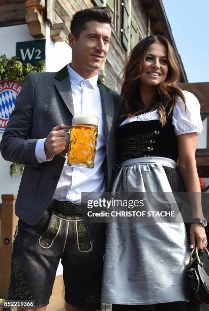 Bayern Munich's Polish forward Robert Lewandowski holds a beer mug as he poses with his wife Anna Stachurska during the traditional visit of members...