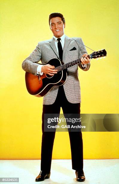 Photo of Elvis PRESLEY, posed, studio, with acoustic guitar