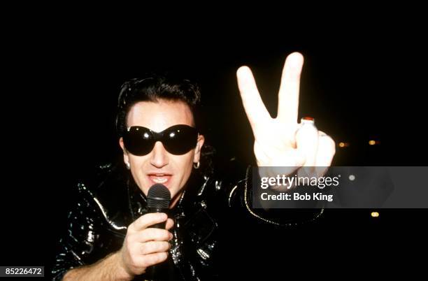 Photo of BONO and U2; Bono performing live onstage at the Aussie Stadium on the Zoo TV tour, Zoomerang leg, wearing sunglasses, doing peace sign,...