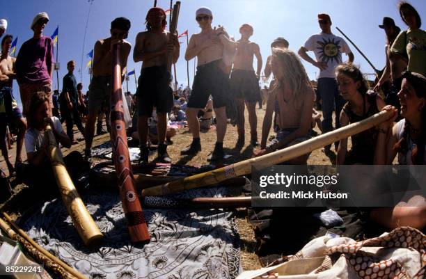 Photo of CROWDS and FANS and DIDGERIDOO and FESTIVALS, a bunch of crusties sit around playing didgeridoos at the 25th anniversary Glastonbury Festival