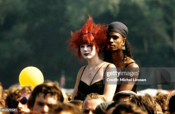 Photo of FESTIVALS and GOTHS and FANS and CROWDS; two goths sit on shoulders in the crowd at a festival in Holland