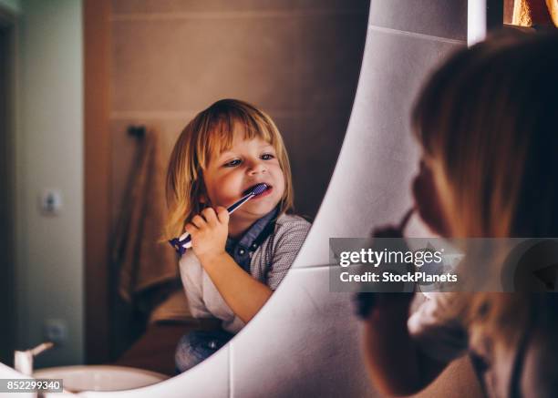 doux jeune garçon est se brosser les dents - se brosser les dents photos et images de collection