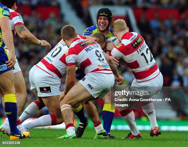 Warrington Wolves' Chris Hill is tackled by Wigan Warriors' Lee Mossop, Michael McIlorum and Liam Farrell during the Super League Grand Final at Old...