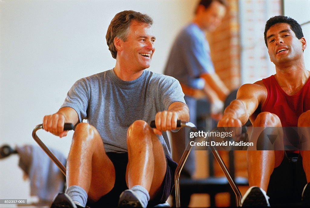 Two men on rowing machines in gym