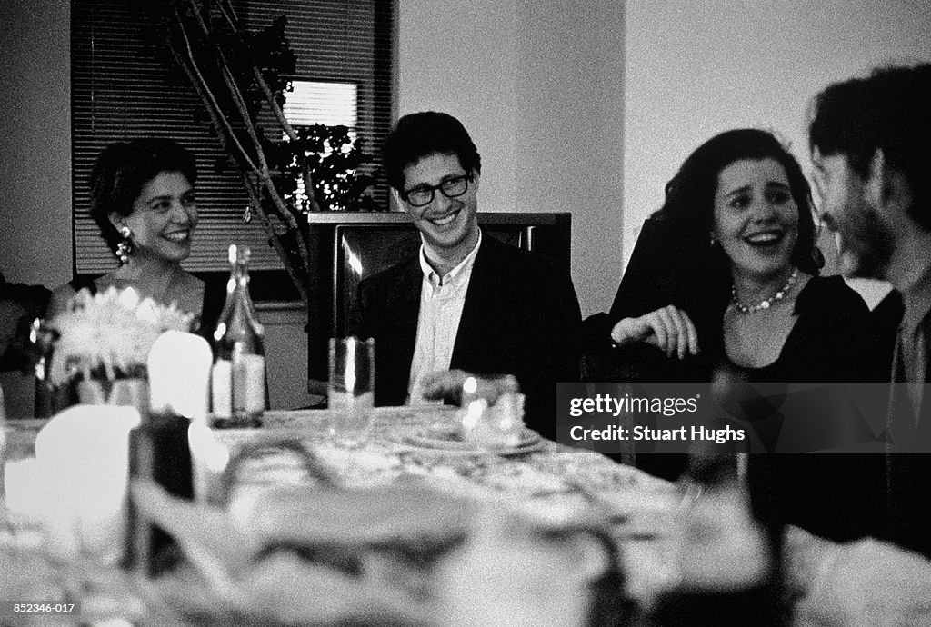 Two couples talking at dinner party (black and white)