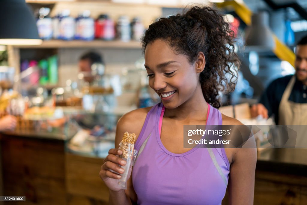 Mujer comiendo una barra de proteína en el gimnasio