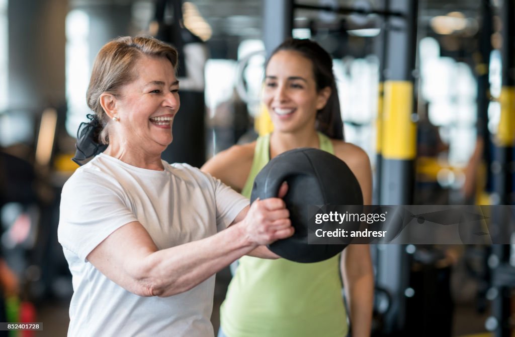 Erwachsene Frau Ausübung in der Turnhalle mit einem personal trainer