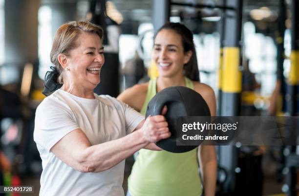 volwassen vrouw trainen op de sportschool met een personal trainer - gewichtheffen krachttraining stockfoto's en -beelden