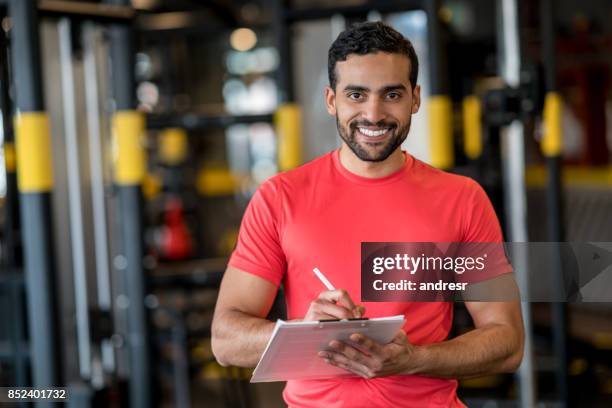 felice personal trainer che lavora in palestra - allenatore foto e immagini stock