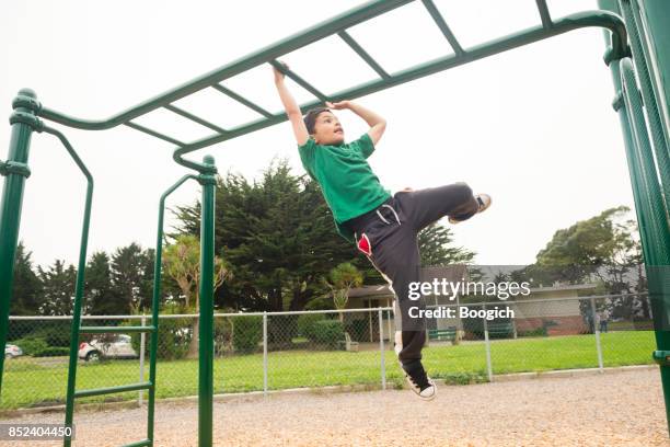 young california boy swinging on monkey bars - monkey bars stock pictures, royalty-free photos & images