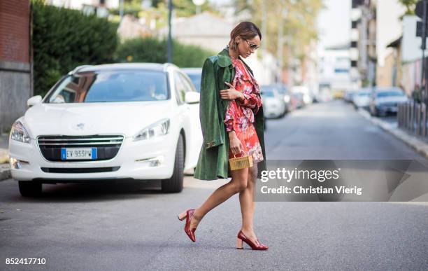 Kat Graham wearing red Gucci dress with floral prints, green Gucci coat, golden mini bag, red heeled shoes, sunglasses is seen during Milan Fashion...