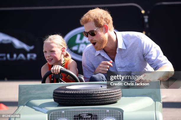 Daimy Gommers drives the car as Prince Harry rides beside her as he visits the Distillery District of the city for the Jaguar Land Rover driving...