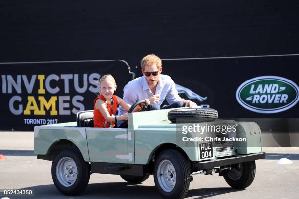 Daimy Gommers drives the car as Prince Harry rides beside her as he visits the Distillery District of the city for the Jaguar Land Rover driving...