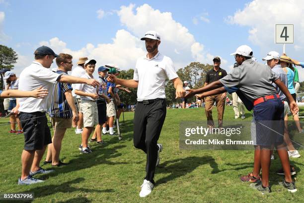 Dustin Johnson of the United States greets fans as he walks to the fifth hole during the third round of the TOUR Championship at East Lake Golf Club...