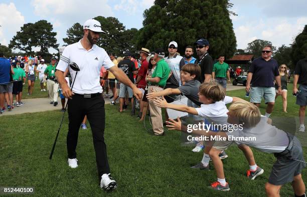 Dustin Johnson of the United States greets fans as he walks to the sixth hole during the third round of the TOUR Championship at East Lake Golf Club...