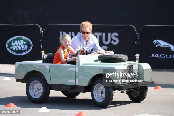 Daimy Gommers drives the car as Prince Harry rides beside her as he visits the Distillery District of the city for the Jaguar Land Rover driving...
