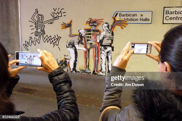 Passers by stop to take photos of a new artwork by street artist Banksy at the Barbican Centre on September 19, 2017 in London, England. The two new...