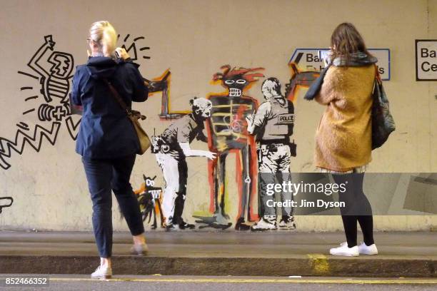 Passers by stop to take photos of a new artwork by street artist Banksy at the Barbican Centre on September 19, 2017 in London, England. The two new...