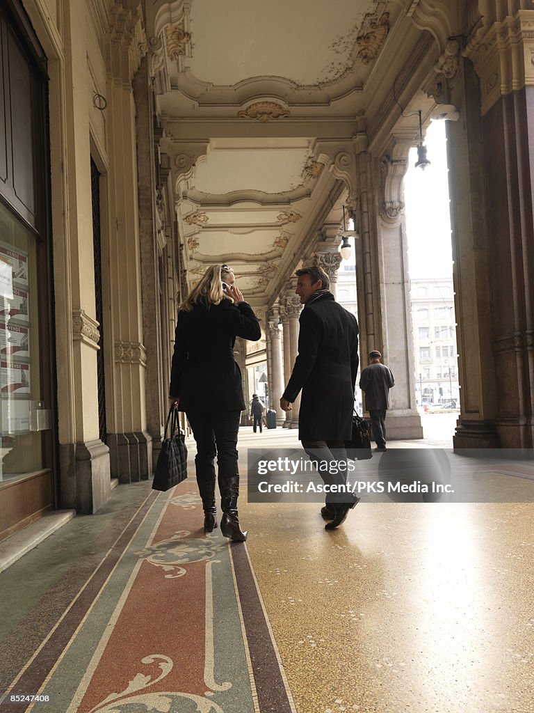 Business couple chat/answer phone while walking