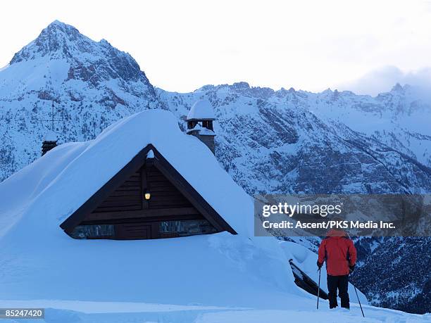 skier approaching mountain hut, lights on - bardonecchia stock-fotos und bilder