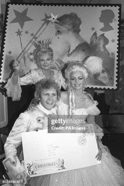 Dame Anna Neagle waves her magic wand over Paul Nicholas and Sarah Payne at the launch of the Post Office's Christmas stamps, which have a pantomime...