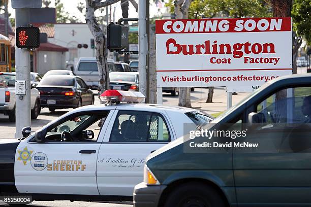 Los Angeles County Sheriff's deputies pass a sign announcing a new business to be opened, March 3, 2009 in Compton, California. The city that became...