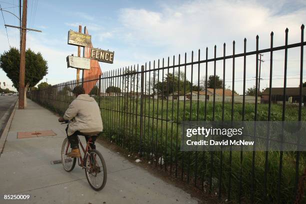 Man bicycles past a lot, vacated years ago when a long-established business failed, March 3, 2009 in Compton, California. The city that became known...