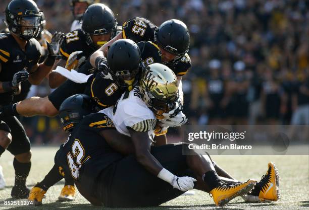 Running back Arkeem Byrd of the Wake Forest Demon Deacons is stopped by defensive back Desmond Franklin of the Appalachian State Mountaineers,...