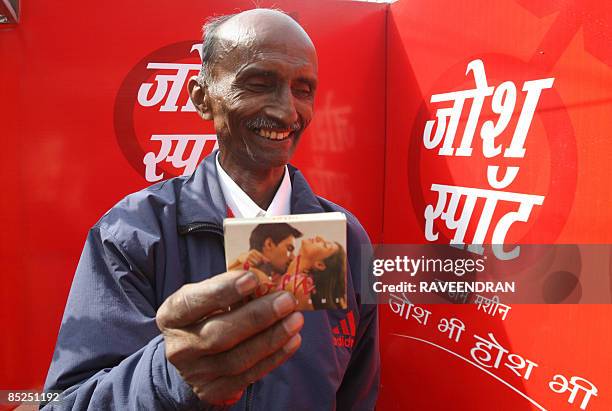 An Indian man poses with a packet of condoms after purchasing it from a condom vending machine in New Delhi on March 5, 2009. The National AIDS...