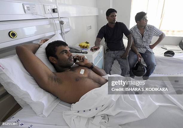 Sri Lankan cricketer Tharanga Paranavitana talks on his mobile phone as he rests on a hospital bed in Colombo on March 5, 2009. Two Sri Lankan...