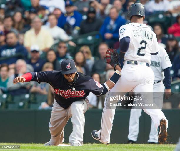 Carlos Santana of the Cleveland Indians has his arm bent backwards as it catches on the hip of Jean Segura of the Seattle Mariners, who was safe at...
