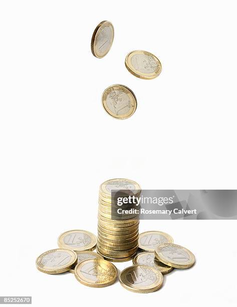 stack of one euro coins with coins falling above. - falling stock pictures, royalty-free photos & images