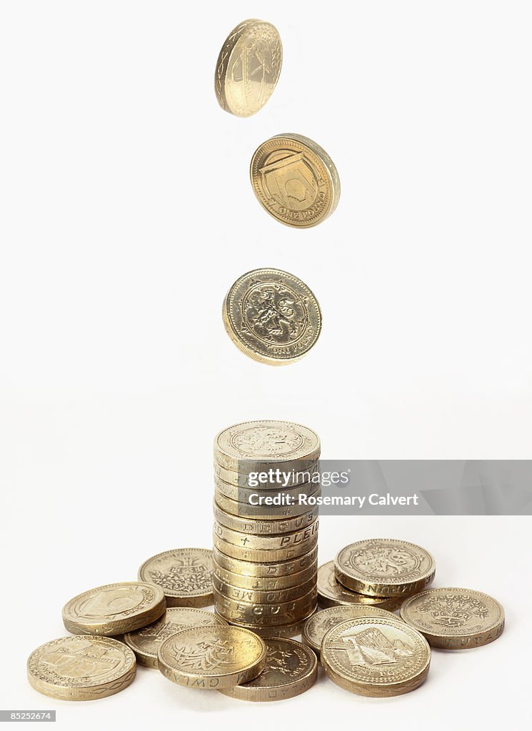 Stack of one pound coins with pound coins falling