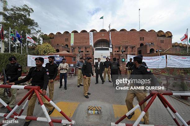 Pakistani policemen stand guard as a bus carrying security personnel enters The Gaddafi Stadium after masked gunmen attacked the Sri Lankan team in...