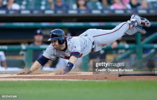 Brian Dozier of the Minnesota Twins dives into home plate to score on a bunt grounder and a throwing error by third baseman Jeimer Candelario of the...