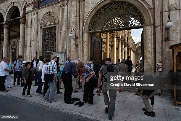 Tourists remove their shoes before entering the 19th century Ottoman-era Muhammad 'Ali mosque, an alabaster covered landmark which dominates the...