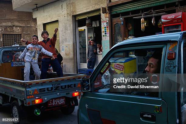 Egyptians boys dance on the back of a truck as traffic passes slowly through the narrow streets of the Bab al-Wazir cemetery, where many of the...
