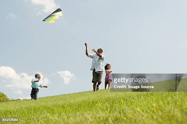 father and children with kite - kite flying photos et images de collection