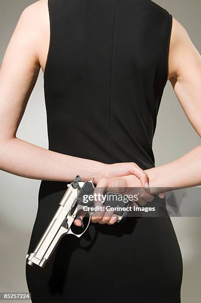 a woman concealing a gun  - hiding behind back stock pictures, royalty-free photos & images