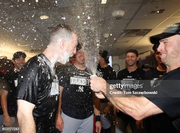 Todd Frazier of the New York Yankees is sprayed by Brett Gardner as they celebrate their playoff-clinching victory during MLB game action against the...