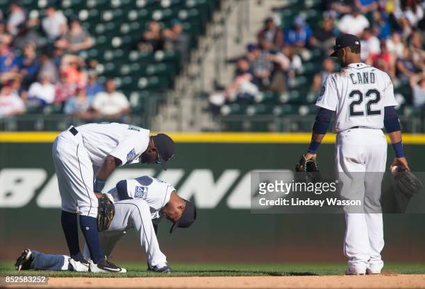 Guillermo Heredia of the Seattle Mariners, left, and Robinson Cano come to check on Jean Segura after Segura was hit in the hand by a throw from...