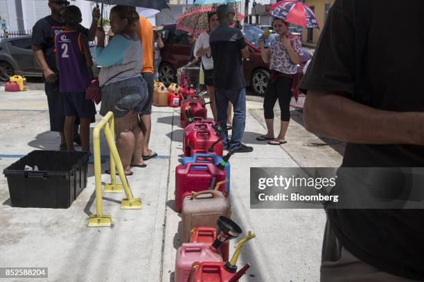 Residents wait for fuel with gas canisters after Hurricane Maria in Quebradillas, Puerto Rico, on Saturday, Sept. 23, 2017. Amid their struggles to...