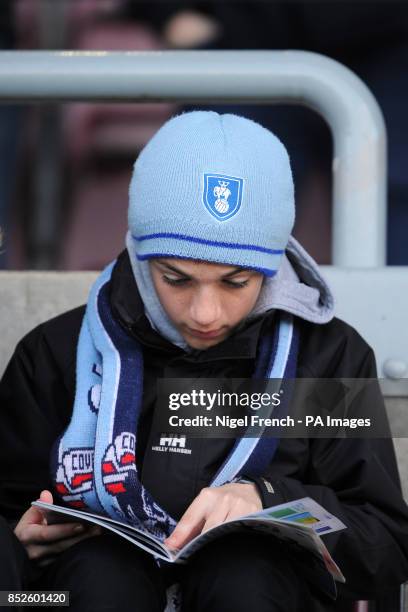 Coventry City fan in the stands at Sixfields reads the match day programme