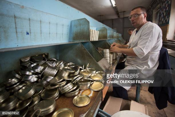 Picture taken on June 12, 2017 shows partially sighted people assembling tin covers in a factory in Donetsk. The factory, which makes tin lids for...